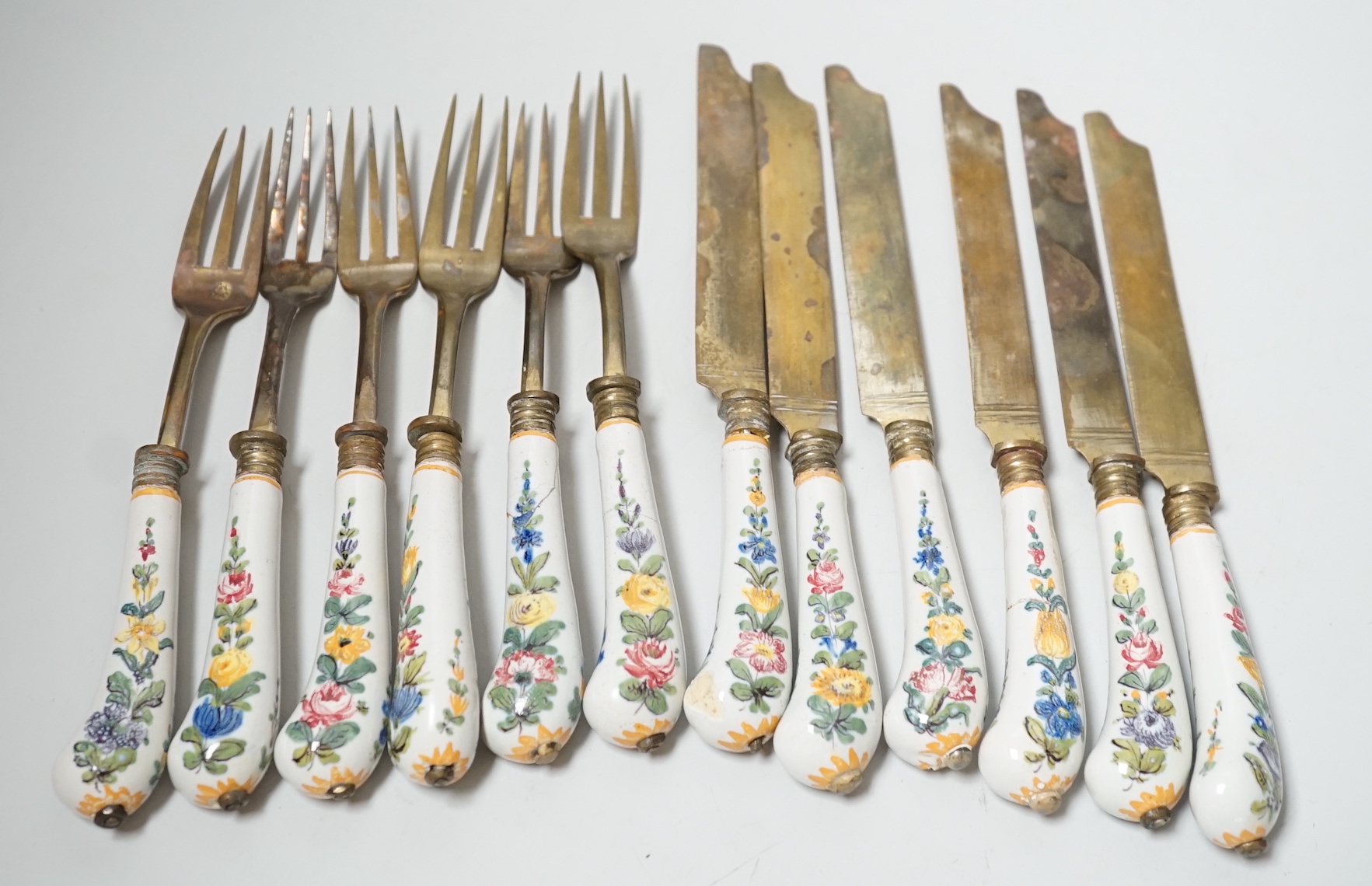 Six pairs of French Faience pistol grip handled knives and forks